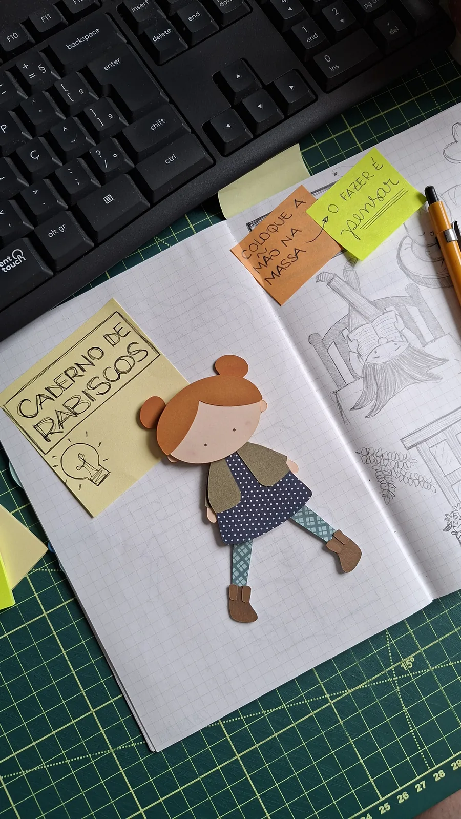 Caderno quadriculado aberto sobre a bancada da artesã